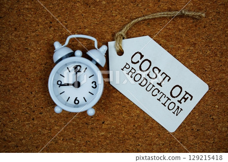 Cost Of Production text on price tag with alarm clock on cork board background 129215418