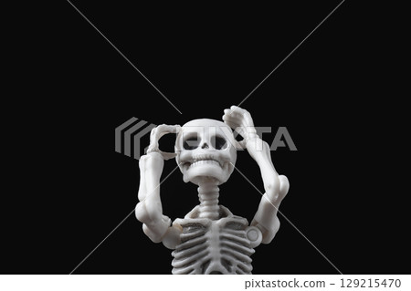 Skeleton figurine hold its head on black. Stressed and sad doll, mental problems, feeling bad, depressed, disappointment, hopeless emotions concept 129215470