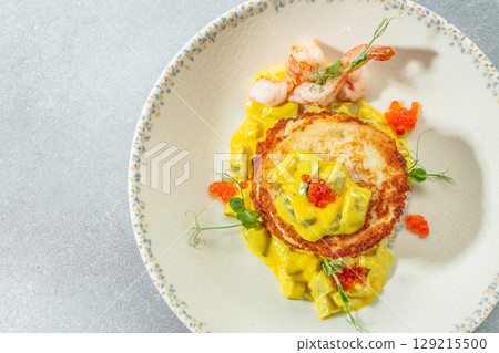 Gourmet potato pancake with shrimp, creamy sauce, and red caviar served on an elegant plate. top view. copy space for text Gourmet potato pancake with shrimp, creamy sauce, and red caviar served on an elegant plate. top view. copy space for text 129215500