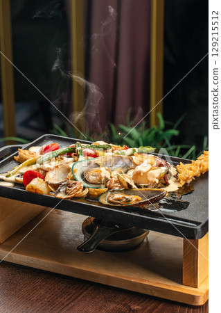 Steaming hot seafood medley with vegetables and creamy sauce served on a sizzling tabletop grill Steaming hot seafood medley with vegetables and creamy sauce served on a sizzling tabletop grill 129215512