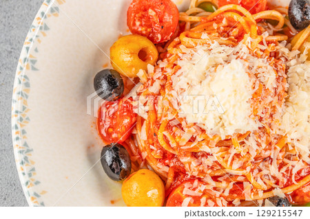 A plate of spaghetti in rich tomato sauce topped with olives and grated cheese 129215547