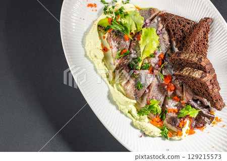 Pickled herring fillets served with creamy mousse, rye bread, red onions, herbs, and fish roe on a white plate. top view. copy space Pickled herring fillets served with creamy mousse, rye bread, red onions, herbs, and fish roe on a white plate. top view. copy space 129215573