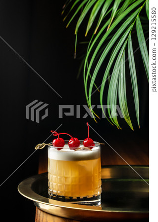 Elegant whiskey sour cocktail with foam and maraschino cherries on a golden tray. copy space 129215580
