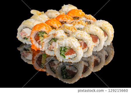 A vibrant selection of assorted sushi rolls filled with fresh fish, cream cheese, and vegetables, topped with sesame seeds and colorful roe on a glossy black background 129215660