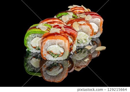 Colorful sushi rolls with salmon, tuna, avocado, cream cheese, and almond flakes arranged on a glossy black surface 129215664