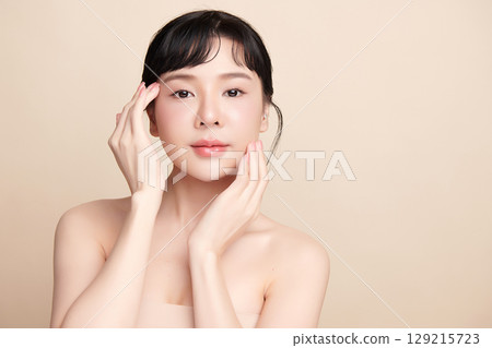 A beautiful young Asian woman with clean, fresh skin against a beige background. Skincare, facial treatment, cosmetology, beauty, and spa. An elegant portrait of an Asian woman. A beautiful young Asian woman with clean, fresh skin against a beige background. Skincare, facial treatment, cosmetology, beauty, and spa. An elegant portrait of an Asian woman. 129215723