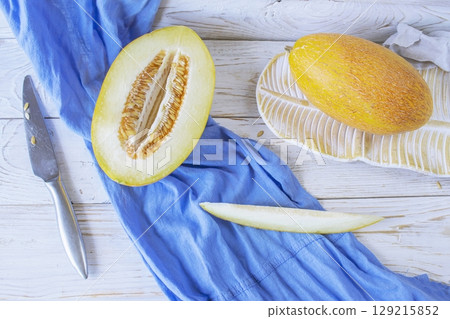 Cut ripe melon. Melon and knife on white wooden background. Top view. Beautiful still life. Cut ripe melon. Melon and knife on white wooden background. Top view. Beautiful still life. 129215852