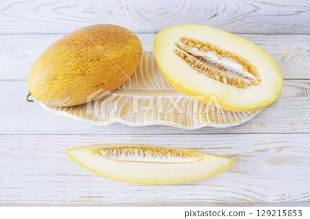 Cut ripe melon. Melon and knife on white wooden background. Top view. Beautiful still life. Cut ripe melon. Melon and knife on white wooden background. Top view. Beautiful still life. 129215853