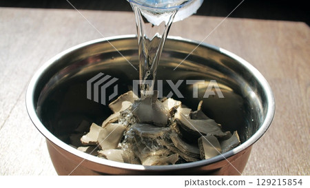 A potter adds water to clay scrap to recycle it, close-up shot A potter adds water to clay scrap to recycle it, close-up shot 129215854