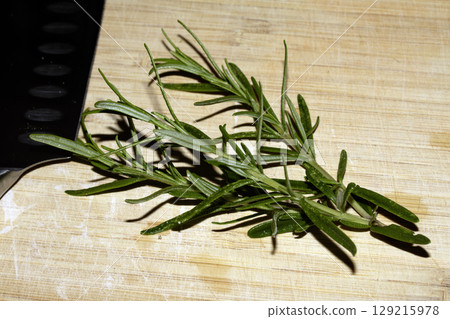 Fresh rosemary sprigs on wooden chopping board waiting to be used in cooking Fresh rosemary sprigs on wooden chopping board waiting to be used in cooking 129215978