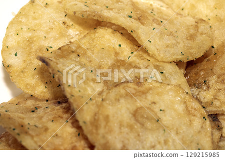 Close up of fresh potato seasoned crisps snack on a white background Close up of fresh potato seasoned crisps snack on a white background 129215985