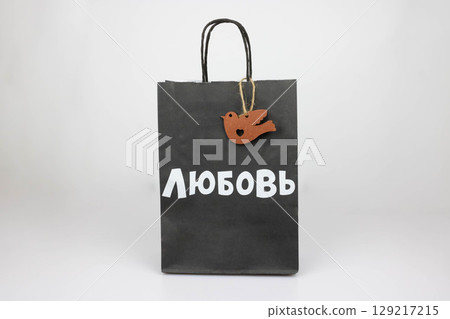 A black paper bag with a wooden bird and the word Love in white Russian letters. The concept of holidays Valentine's Day March 8th family day Easter. 129217215