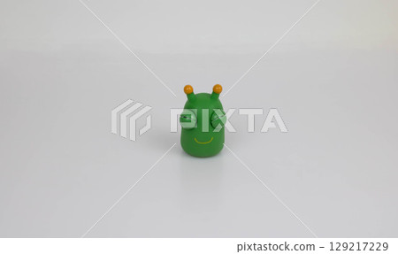 Funny cute green monster, rubber toy on a white background 129217229