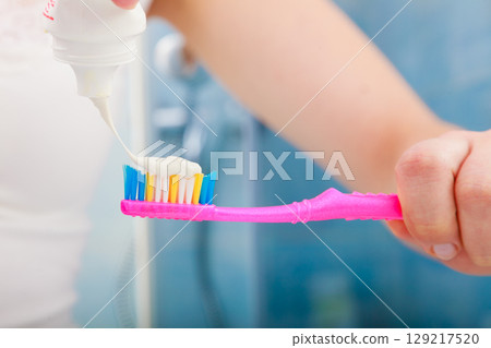 Woman hands putting toothpaste on toothbrush Woman hands putting toothpaste on toothbrush 129217520