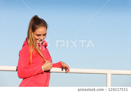 Woman in sportswear standing on dyke by sea Woman in sportswear standing on dyke by sea 129217551
