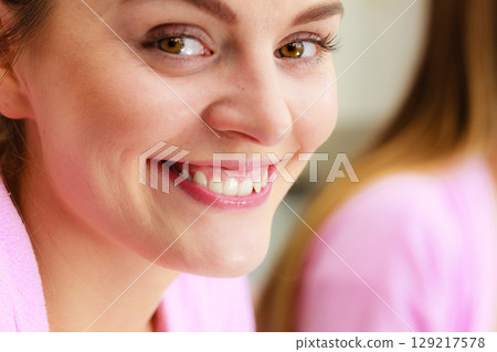 young woman looking at mirror in bathroom young woman looking at mirror in bathroom 129217578