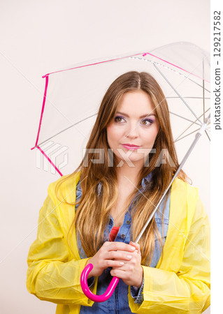 Woman wearing waterproof coat holding umbrella Woman wearing waterproof coat holding umbrella 129217582