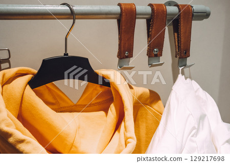 in fitting room clothing store, hangers clothes and leather hooks for clothes hang on metal bar. 129217698