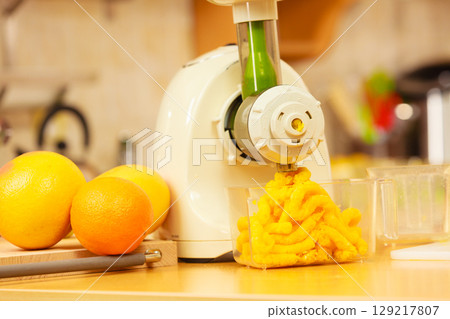 Making orange juice in juicer machine in kitchen 129217807