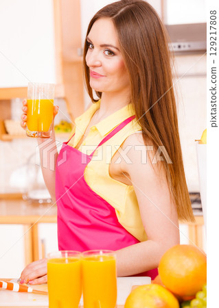 Woman in kitchen drinking fresh orange juice Woman in kitchen drinking fresh orange juice 129217808