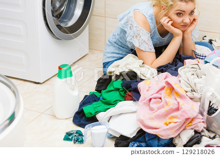 Unhappy girl sorting dirty clothes laundry. Unhappy girl sorting dirty clothes laundry. 129218026
