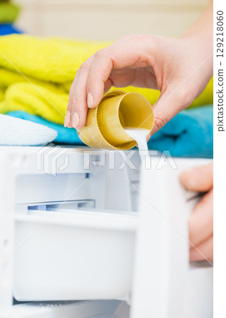 Person pouring fabric softener into washing machine Person pouring fabric softener into washing machine 129218060