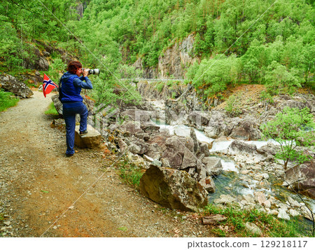 Tourist with norwegian flag on mountains path Tourist with norwegian flag on mountains path 129218117