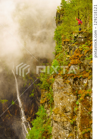 Tourist woman by Voringsfossen waterfall, Norway Tourist woman by Voringsfossen waterfall, Norway 129218121