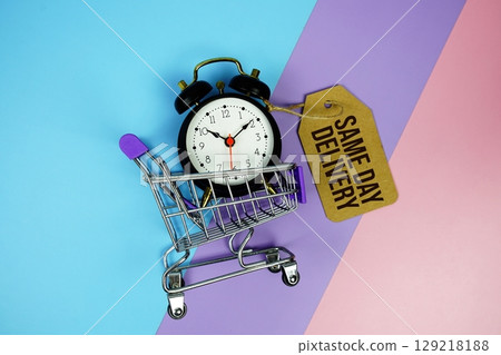 Same Day Delivery text on price tag with alarm clock and trolley shopping cart on pink, purple, blue geometric background Same Day Delivery text on price tag with alarm clock and trolley shopping cart on pink, purple, blue geometric background 129218188