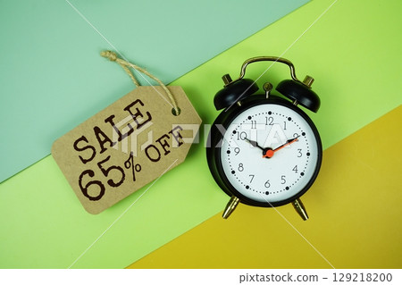 Sale 65% off text on price tag with alarm clock on green, yellow geometric background Sale 65% off text on price tag with alarm clock on green, yellow geometric background 129218200