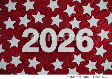 Happy New Year 2026 number and silver star confetti on red glitter background Happy New Year 2026 number and silver star confetti on red glitter background 129218270