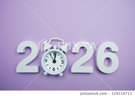 Happy New Year 2026 with alarm clock on purple background Happy New Year 2026 with alarm clock on purple background 129218713