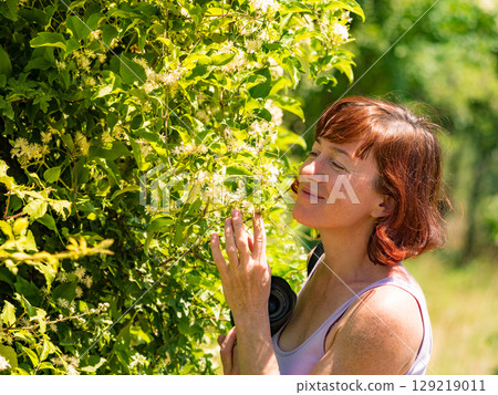 Woman smelling white flowers Woman smelling white flowers 129219011