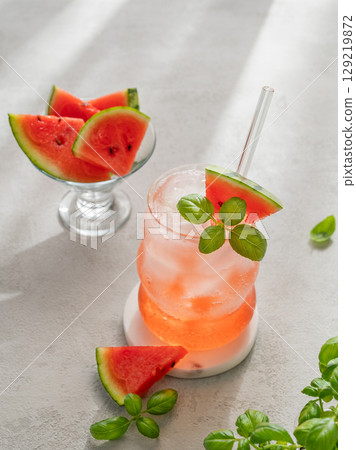 Watermelon mojito cocktail with ice and mint in a glass on a light background with fresh slices 129219872