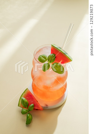 Watermelon mojito cocktail with ice and mint in a glass on a yellow background with shadow. 129219873