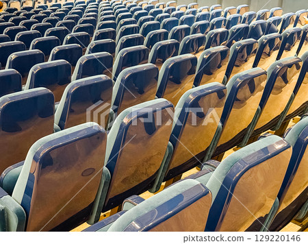 Multiple rows of glossy auditorium chairs in diagonal perspective. Organization, anticipation, and event readiness in a structured public seating environment. 129220146
