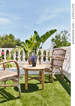 Cozy terrace with rattan chairs and green plants 129221245