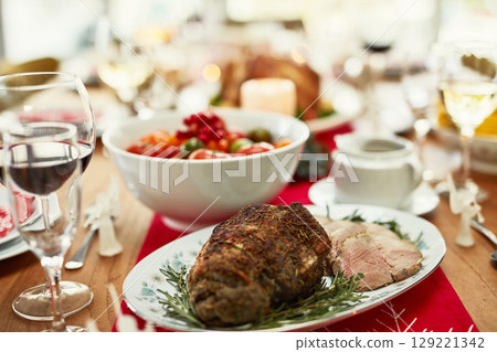 Background, roast beef and thanksgiving food on dining table for dinner party, celebration and christmas, family lunch and meal at home. Closeup of ham, meat and festive feast in fine dining room 129221342