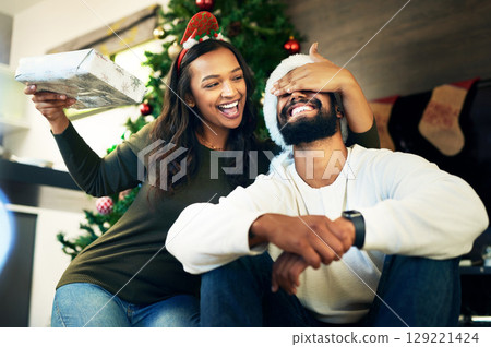 Couple, bonding and surprise christmas gift in house or home living room for celebration, festive holiday or Portugal vacation. Smile, happy or xmas man and woman with present box in love or support 129221424