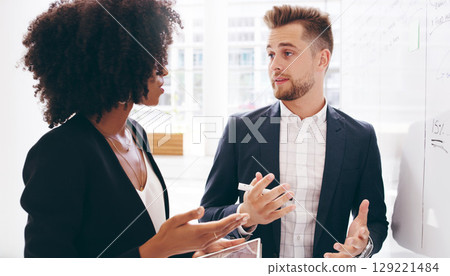 Diversity, black woman and businessman brainstorming on a whiteboard in a meeting for a strategy, innovation or solution. Ideas, teamwork and creative startup company developer talking to an employee 129221484