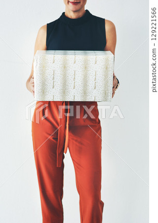 Woman holding, box or gift in studio for birthday, christmas or celebration with fashion, clothes or smile. Model, present or hands hold package for kindness, congratulations or party by background 129221566