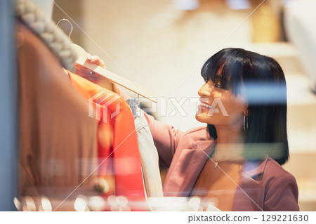 Woman, clothes shopping and retail fashion worker in store or customer decison in luxury boutique. Black woman, search rail and designer thinking for stylist, clothing choice and shirt apparel Woman, clothes shopping and retail fashion worker in store or customer decison in luxury boutique. Black woman, search rail and designer thinking for stylist, clothing choice and shirt apparel 129221630