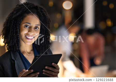 Face, tablet and night with a business black woman at work overtime late in her company office. Portrait, technology and dark with a female employee working to finish a task or project by deadline 129221688
