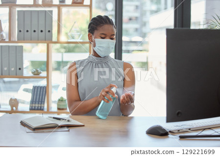 Covid, mask and hand sanitizer with a business black woman cleaning while working in her office. Health, safety and sanitizing with a female employee using disinfectant during the corona virus 129221699