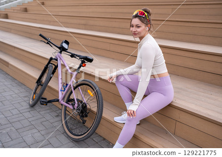 Portrait of Sporty Woman with her bicycle for vacation, holiday and happiness in park or outdoor. Female person on bench for rest, relax and break Portrait of Sporty Woman with her bicycle for vacation, holiday and happiness in park or outdoor. Female person on bench for rest, relax and break 129221775