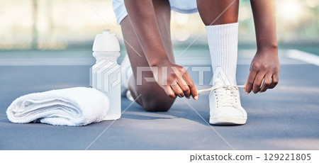 Tennis, athlete and sports feet tying her shoe laces ready for game, competition or training outdoor with water bottle gear. Fitness sneakers of black woman foot on ground zoom in workout motivation 129221805