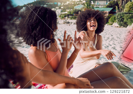 Travel, beach and funny friends on a holiday vacation in summer laughing at a crazy joke together with freedom. Smile, relax and happy young African women enjoy quality time on a sand picnic at sea 129221872