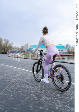 A Woman Riding Her Bicycle by the Water on a Cloudy Day Amidst Natures Beauty A Woman Riding Her Bicycle by the Water on a Cloudy Day Amidst Natures Beauty 129221986