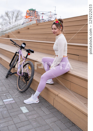 Portrait of Sporty Woman with her bicycle for vacation, holiday and happiness in park or outdoor. Female person on bench for rest, relax and break Portrait of Sporty Woman with her bicycle for vacation, holiday and happiness in park or outdoor. Female person on bench for rest, relax and break 129222033