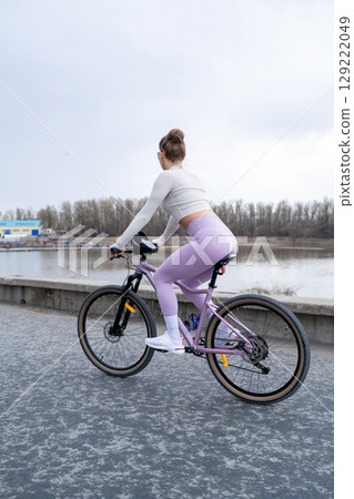 A Woman Riding Her Bicycle by the Water on a Cloudy Day Amidst Natures Beauty A Woman Riding Her Bicycle by the Water on a Cloudy Day Amidst Natures Beauty 129222049